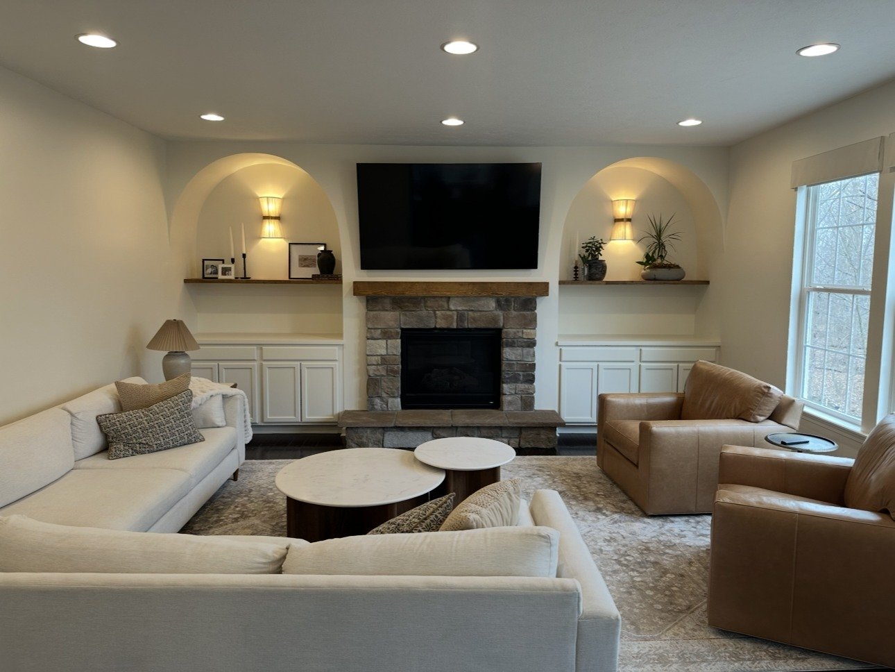 Great room after remodel with arched built-ins and stone fireplace