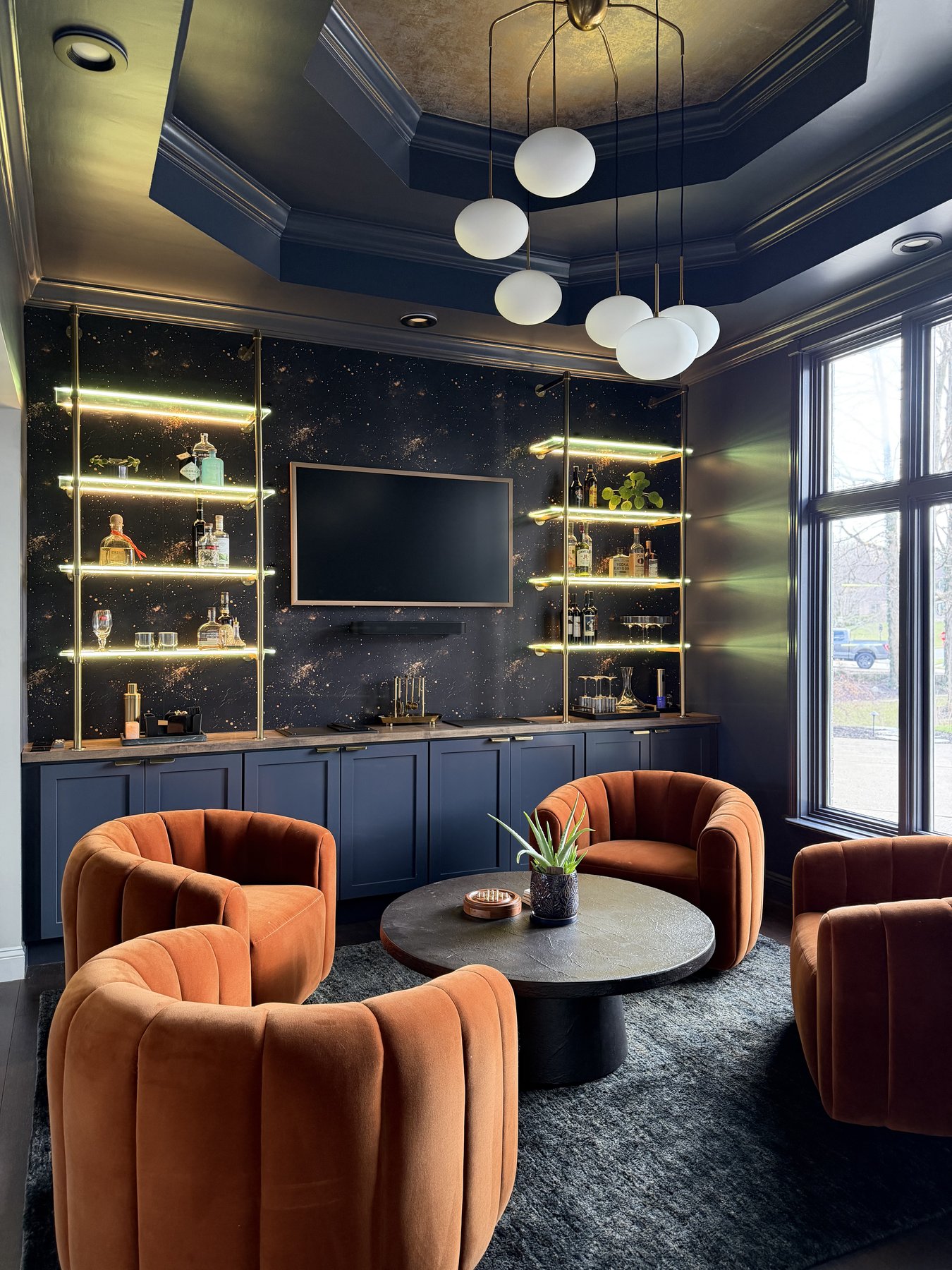 Custom lounge with coffered foil ceiling, galaxy-print wallpaper, and navy built-in cabinetry